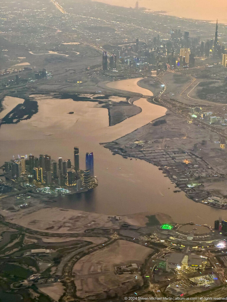 Aerial view of Dubai waterfront towers, roads, and open development land.