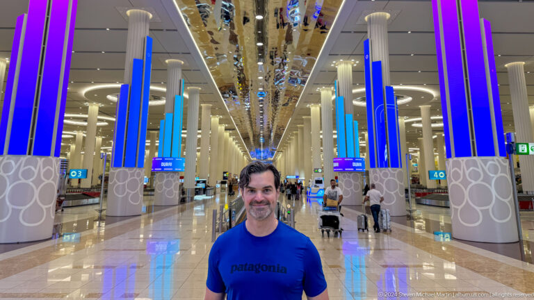 Smiling man standing inside a bright Dubai airport terminal.