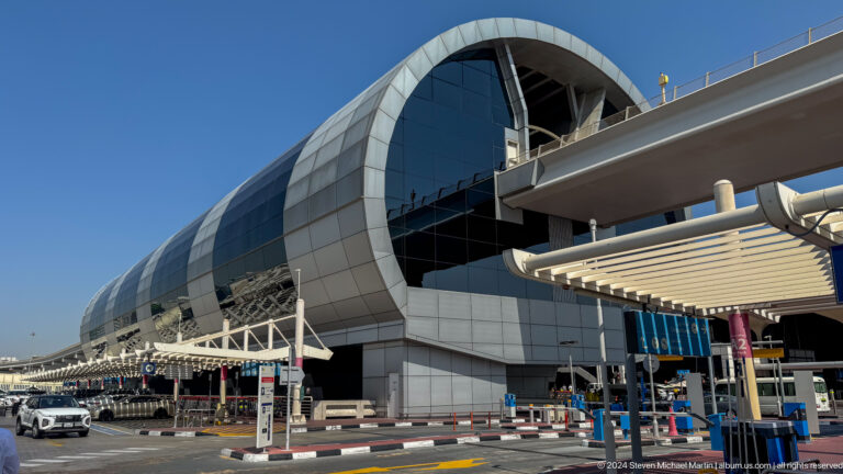 Curved glass-and-metal exterior of a Dubai airport terminal.