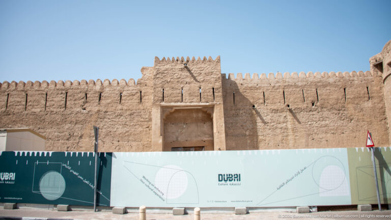 Sand-colored heritage gateway with crenellated walls in Dubai.