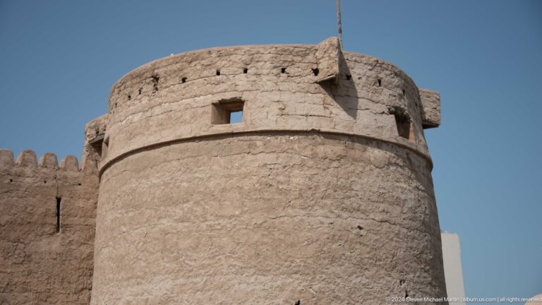 Round sand-colored watchtower with small openings and timber projections.