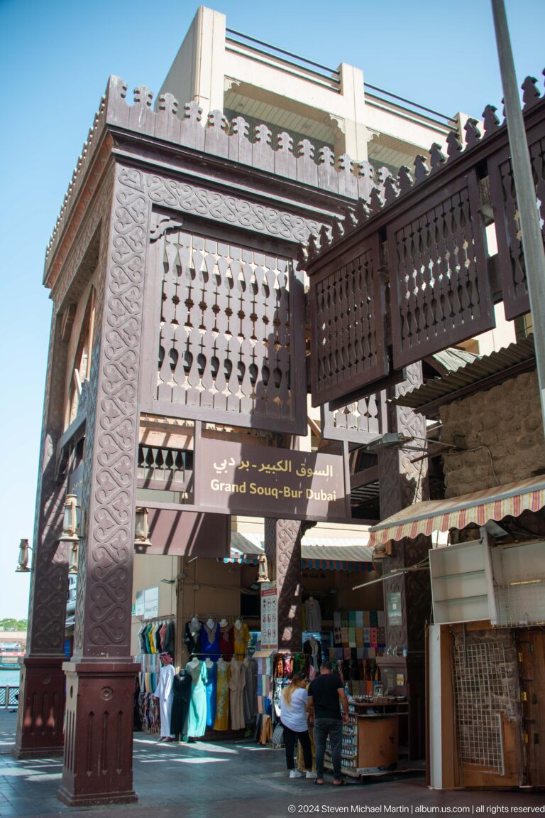 Grand Souq Bur Dubai sign beneath wooden lattice balconies.