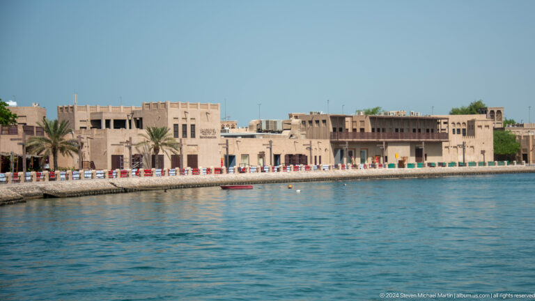 Long row of sand-colored heritage buildings along Dubai Creek.