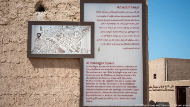 Interpretive panel about Al Shindagha houses beside a heritage wall.