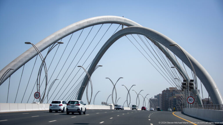 Roadway view beneath the white arches of Infinity Bridge.