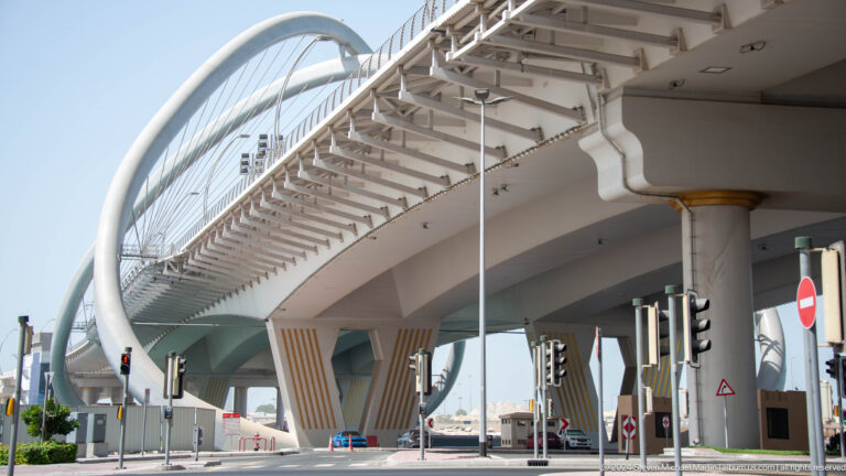 Underside of Infinity Bridge with white piers and curved supports.