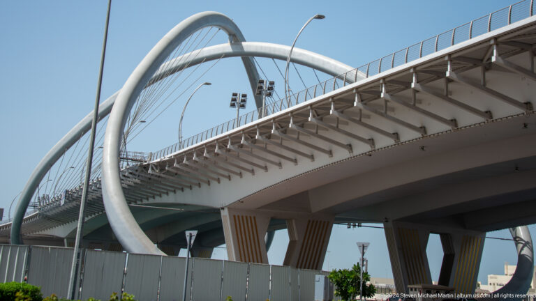 Side view of Infinity Bridge with a looping white arch support.