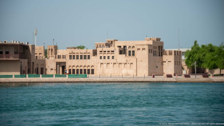 Cream-colored waterfront complex with arcades and wind towers.
