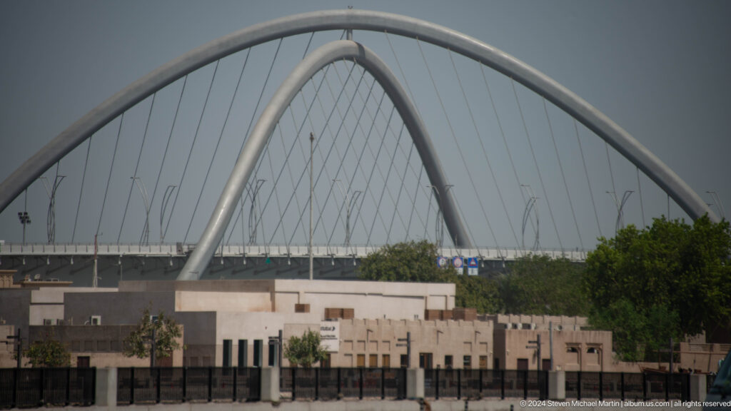 Infinity Bridge arch visible behind low waterfront buildings.