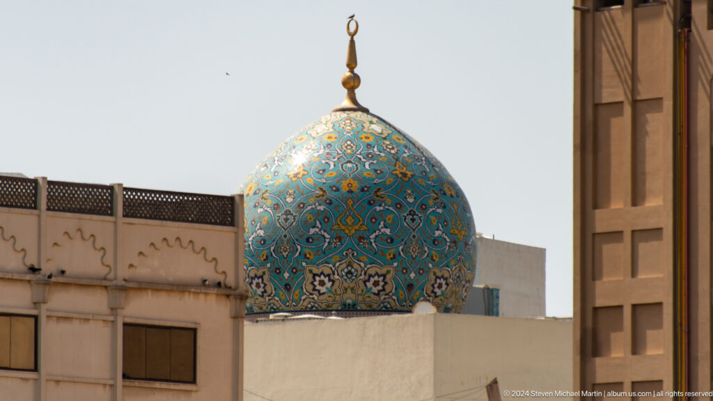 Blue and gold floral-tiled mosque dome with crescent finial.