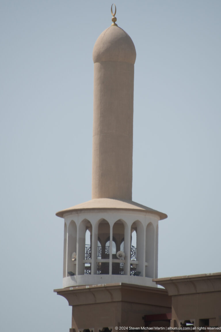Close view of a white mosque minaret balcony and shaft.
