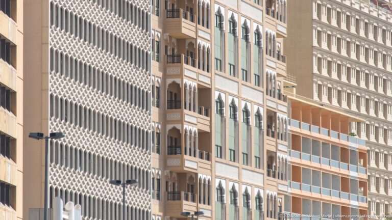 Dense cluster of Dubai building façades with balconies and screens.