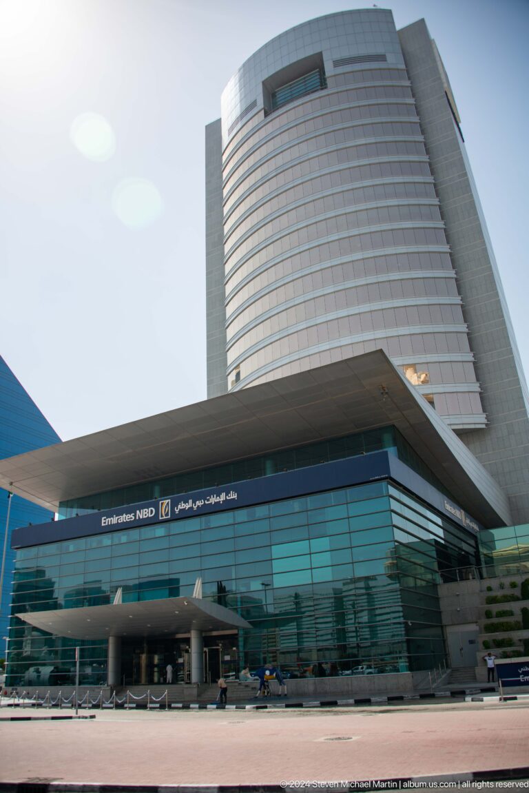 Modern Dubai commercial tower with curved glass façade and bilingual signage.