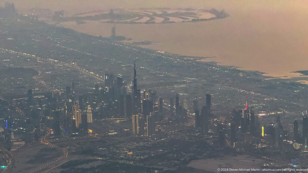 Hazy aerial view of Dubai’s high-rise skyline at sunset.