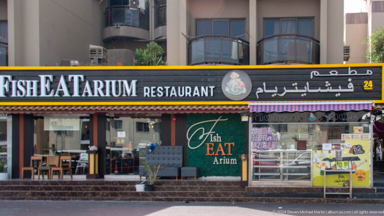 Row of Dubai restaurant storefronts with English and Arabic signs.