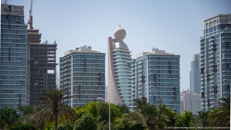 Dubai skyline cluster with varied modern towers and a curved rooftop feature.