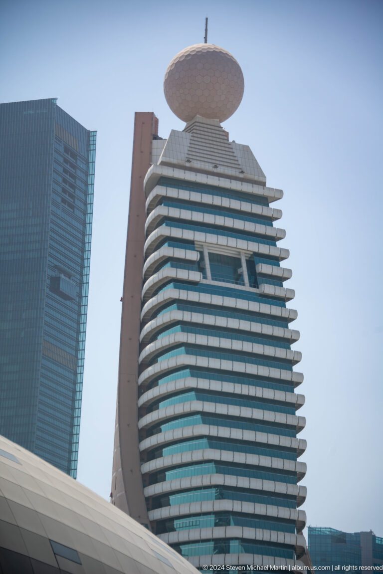 Close view of a Dubai high-rise with stepped balconies and dark glass.