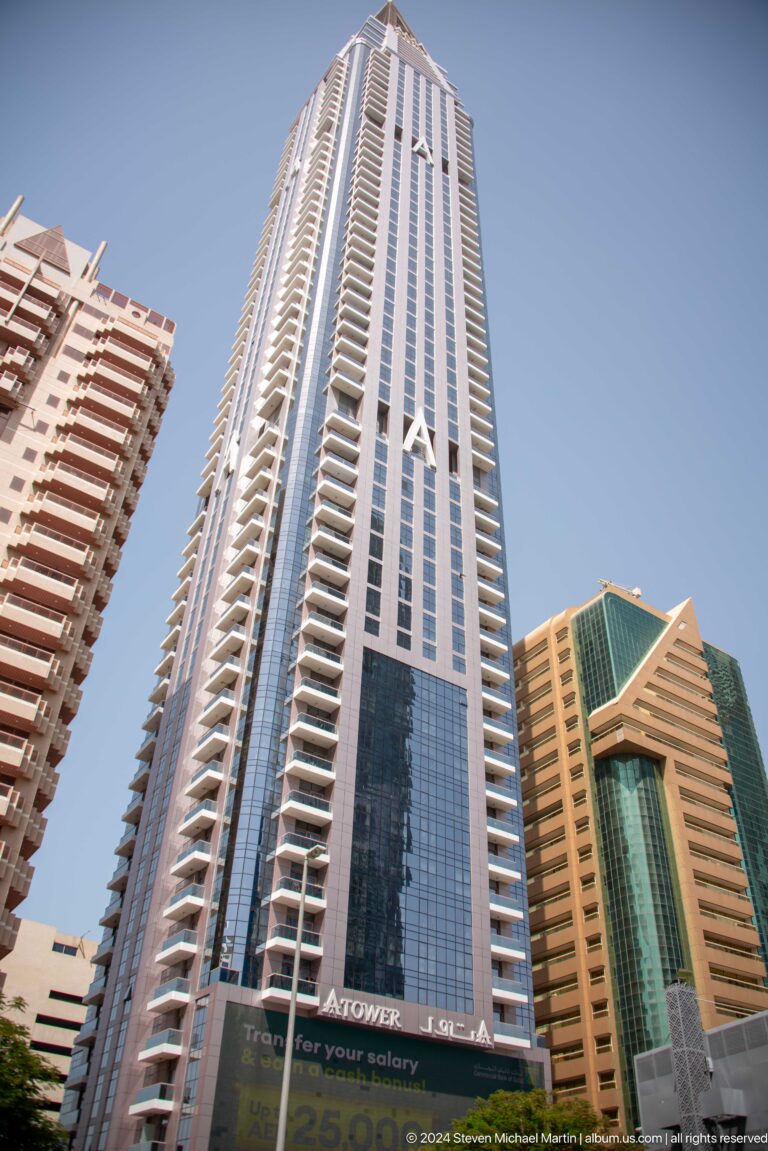 Upward view between tall Dubai residential towers.