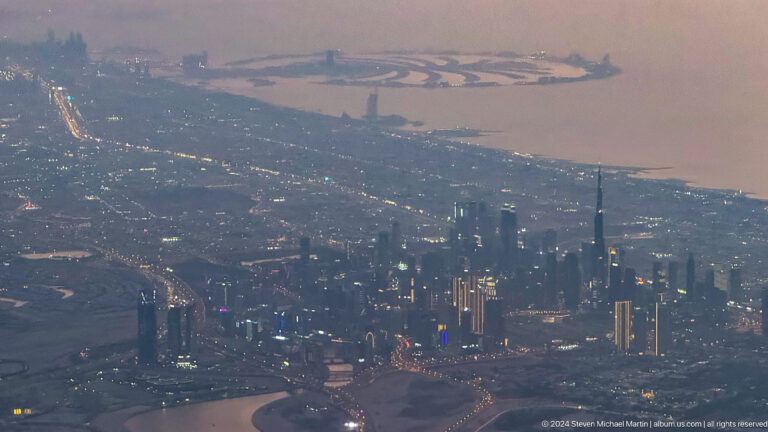 Aerial view of Dubai towers across a broad urban plain.