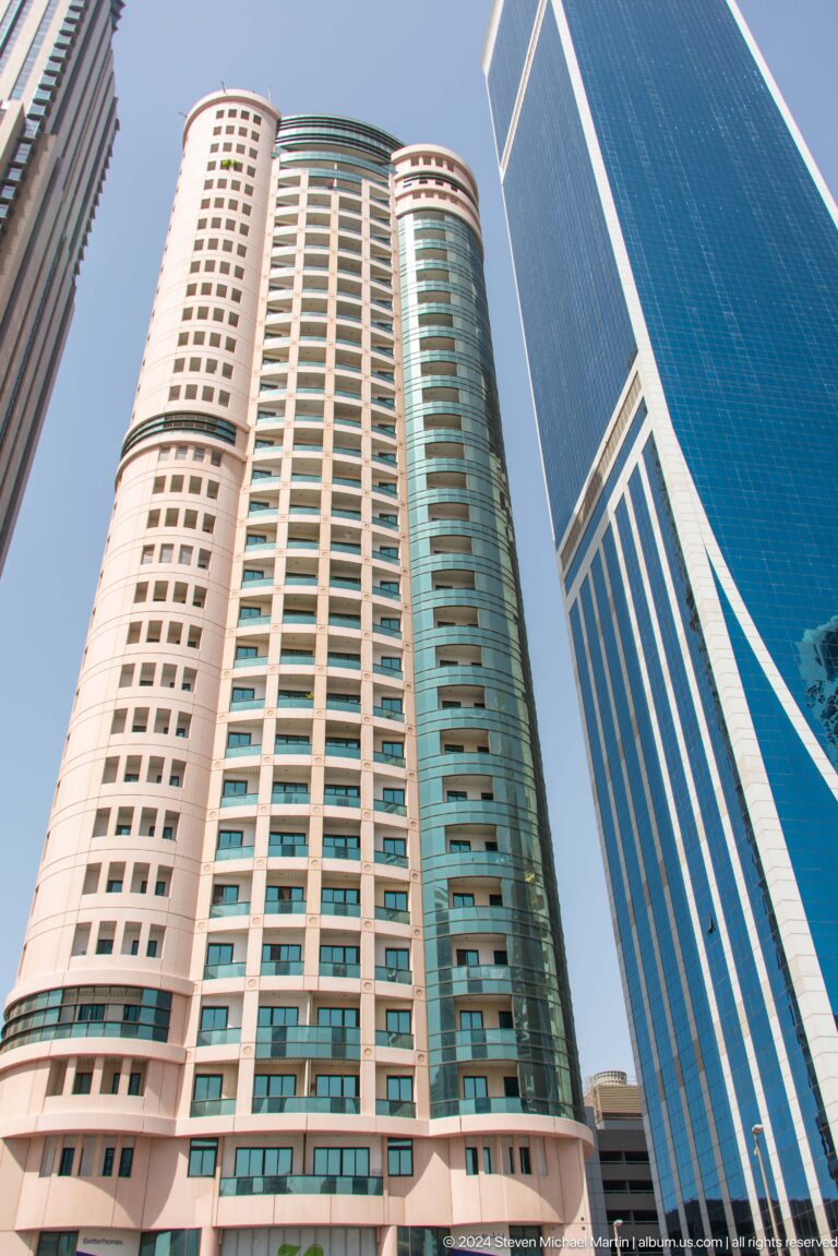 Upward view of tan and blue Dubai high-rise façades.