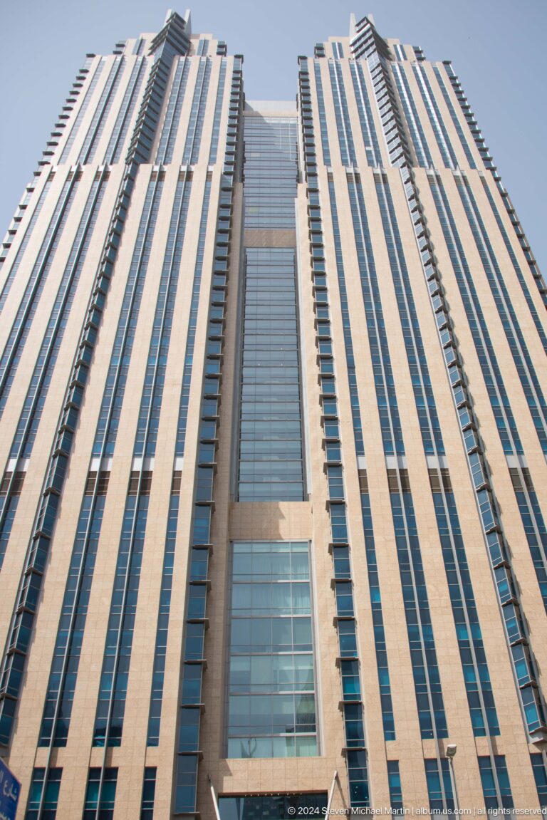 Striped Dubai high-rise façade viewed from below.
