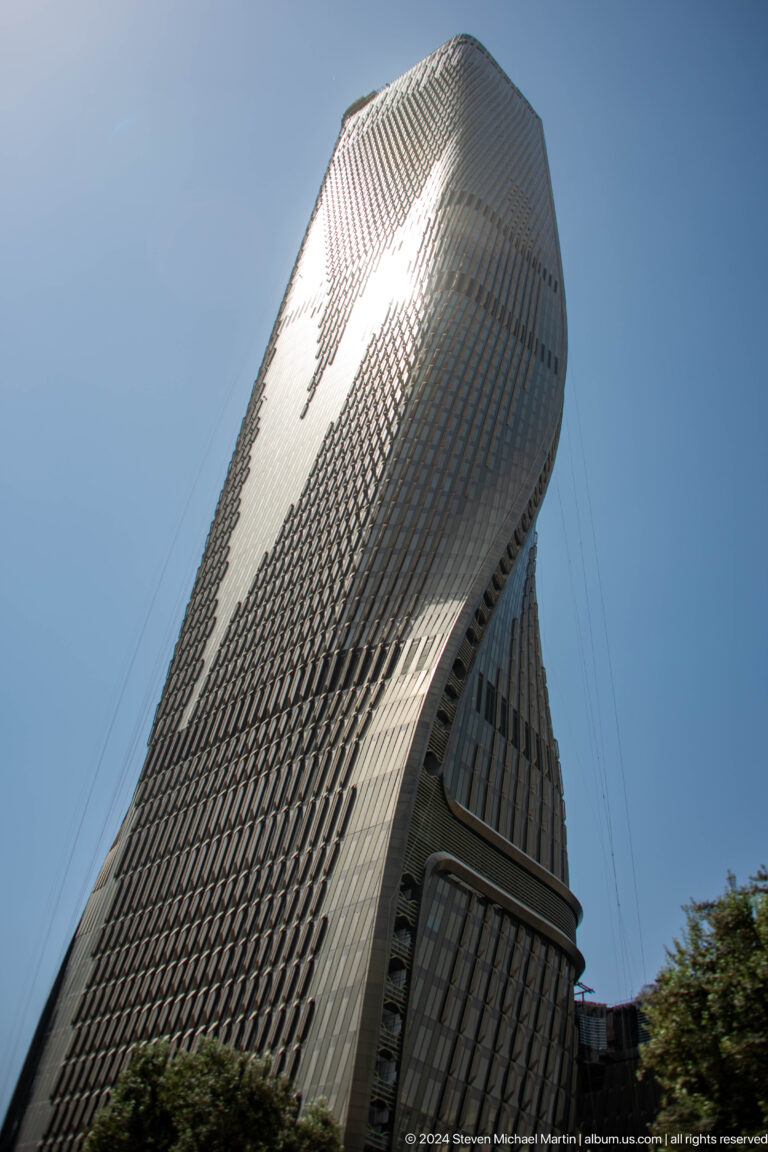 Extreme upward view along a curved Dubai high-rise façade.