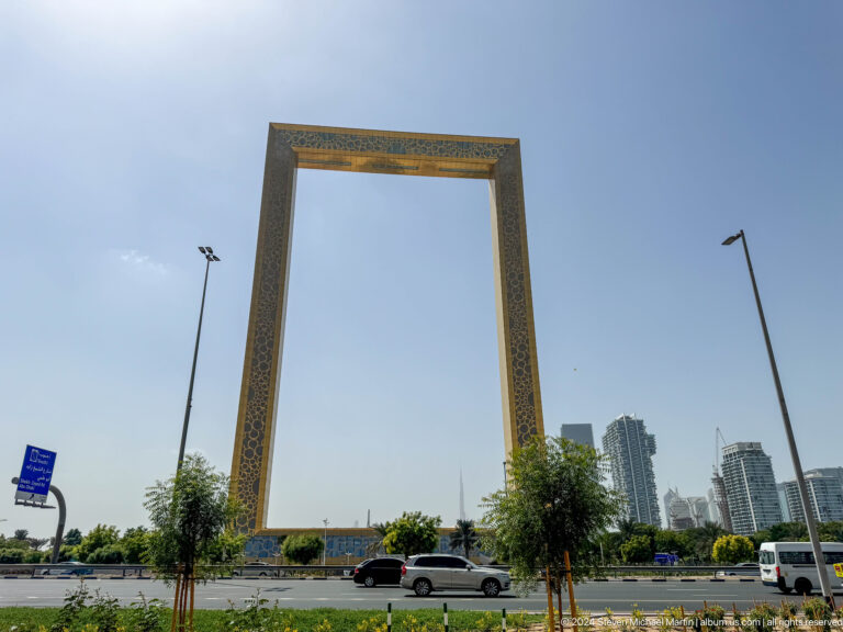 Dubai Frame monument rising beside a roadway and trees.