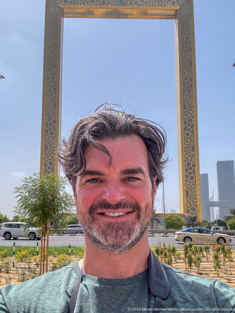 Smiling man posing with Dubai Frame behind him.