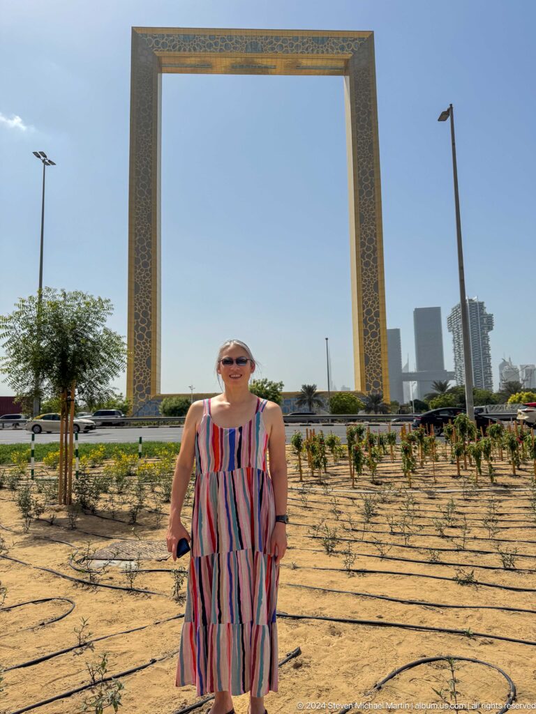 Woman in sunglasses standing in front of Dubai Frame.