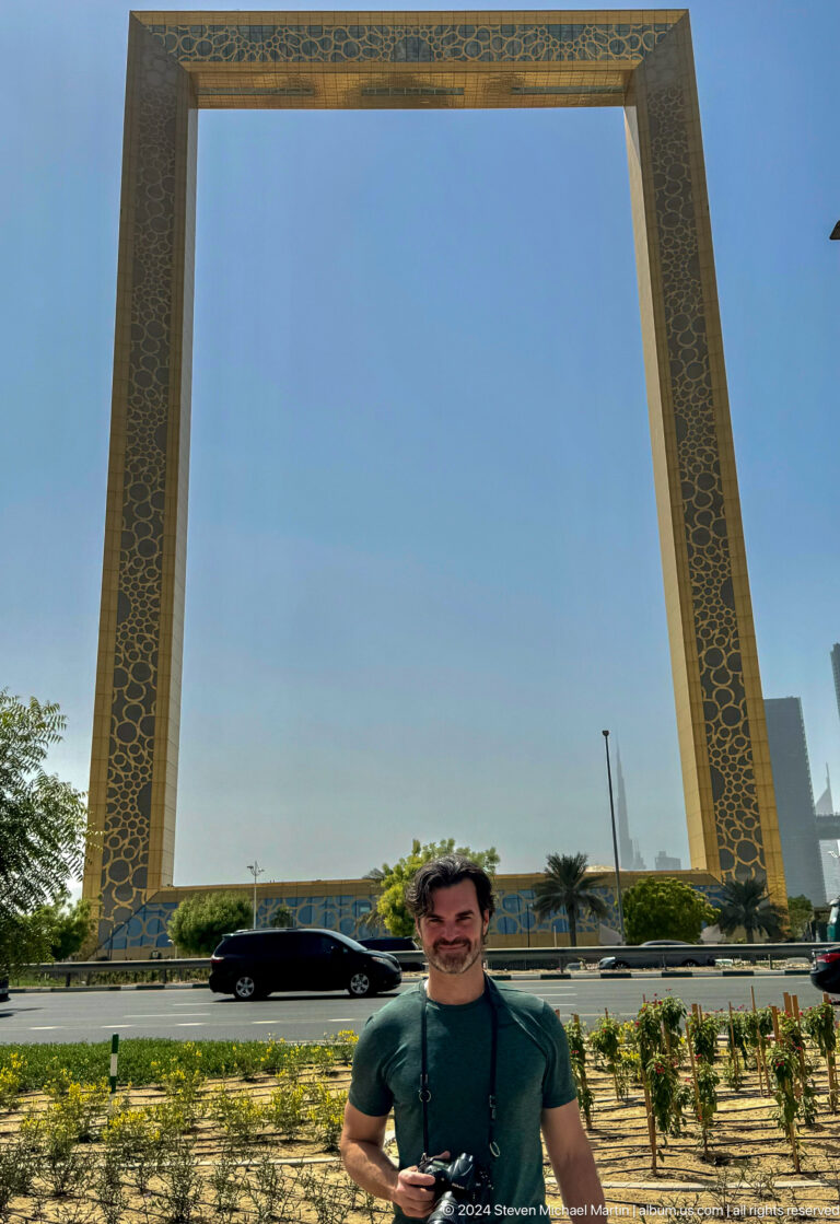 Partially cropped traveler beneath the tall gold uprights of Dubai Frame.