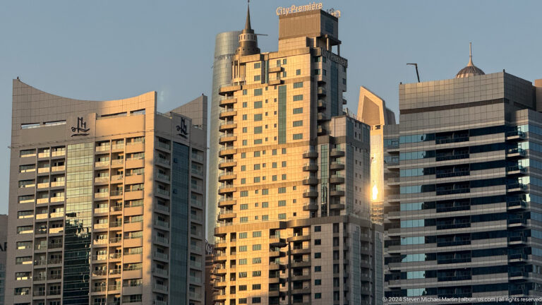 Sunlit cluster of beige and gold Dubai high-rise buildings.