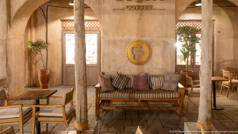 Wooden bench with striped cushions against rough plaster walls and a small wall decoration in a traditional-style interior in Al Seef, Dubai.