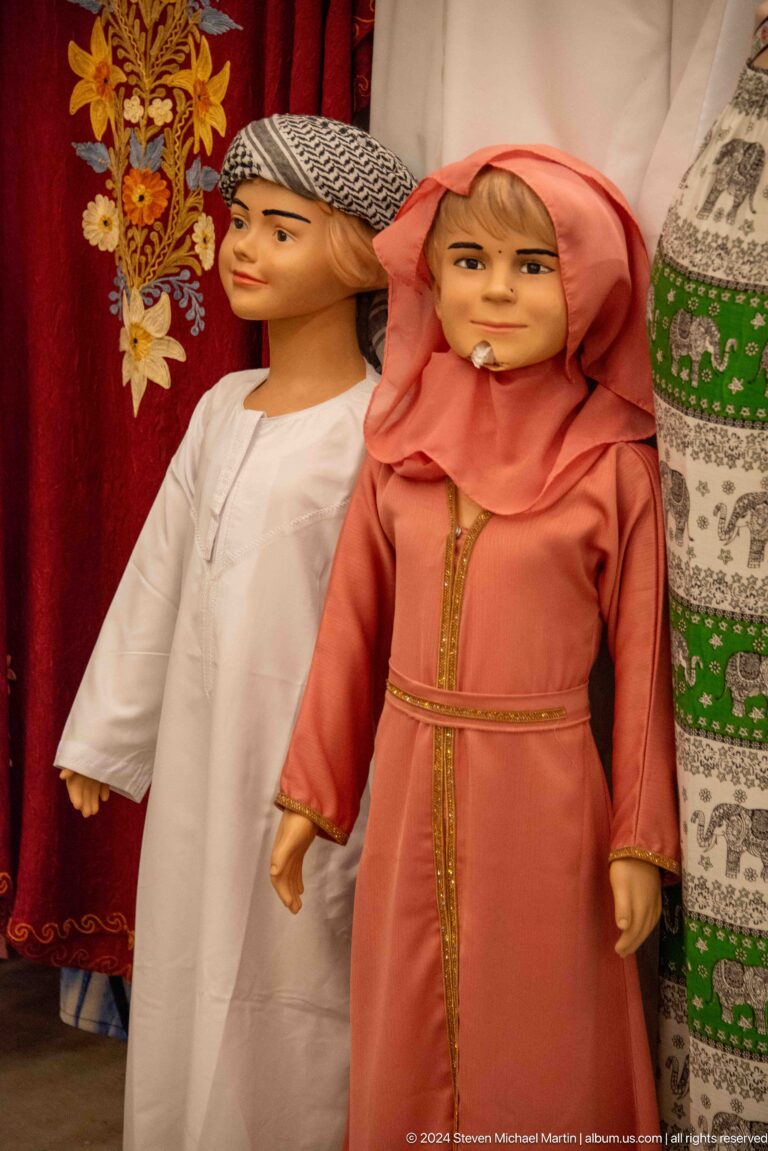 Two torso mannequins in an Al Seef Dubai shop wear long modest garments, one styled with a peach-colored headscarf and decorative trim at the neckline.
