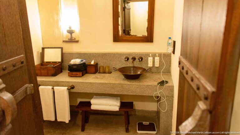 Heritage-style hotel bathroom vanity at Al Seef Dubai with a stone countertop, round vessel basin, framed mirror, toiletries, and folded white towels beneath the counter.