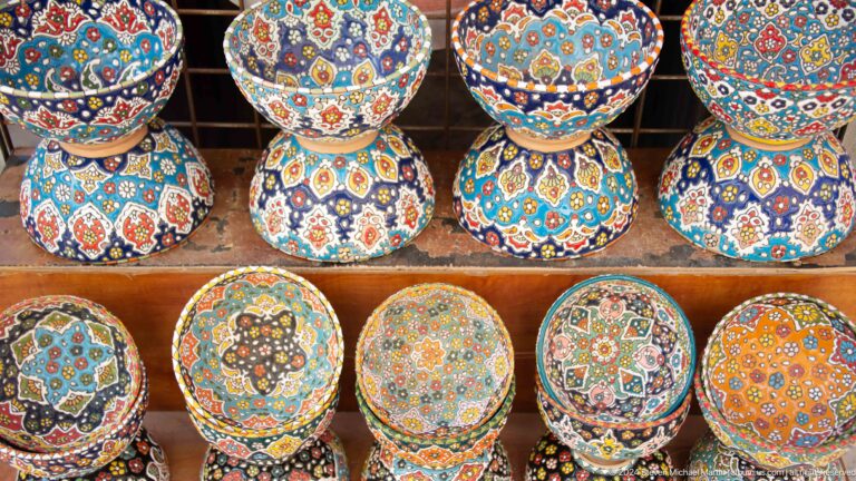 Close-up of overlapping hand-painted ceramic bowls with bright floral and geometric patterns in blue, red, yellow, and turquoise.