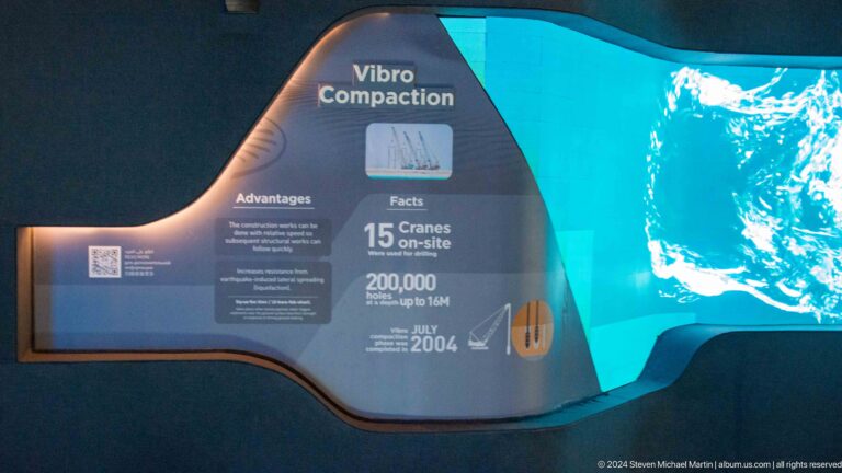 Vibro Compaction exhibition panel with construction facts and a blue video screen.