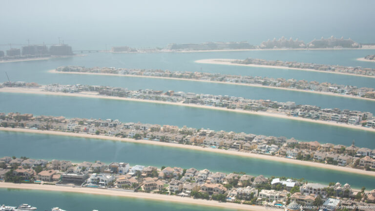 Several Palm Jumeirah fronds lined with villas and separated by turquoise water channels.
