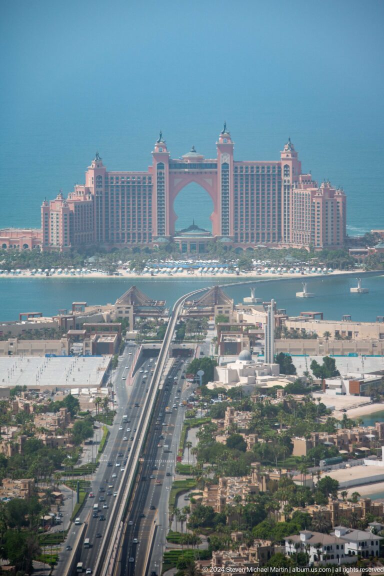 Atlantis The Palm seen beyond low resort buildings, waterways, and transport structures.
