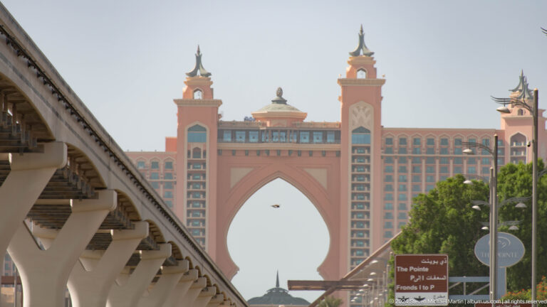 Atlantis The Palm arch framed by a monorail viaduct and a sign for The Pointe.