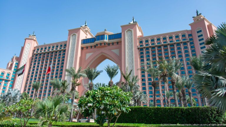Atlantis The Palm's pink facade and central arch above palms and gardens.