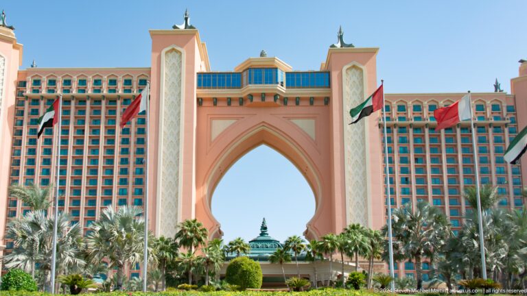 Centered view of Atlantis The Palm's arch, entrance, palms, and UAE flags.