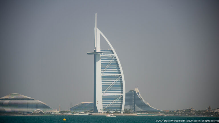 Burj Al Arab centered between low wave-shaped Jumeirah resort buildings.