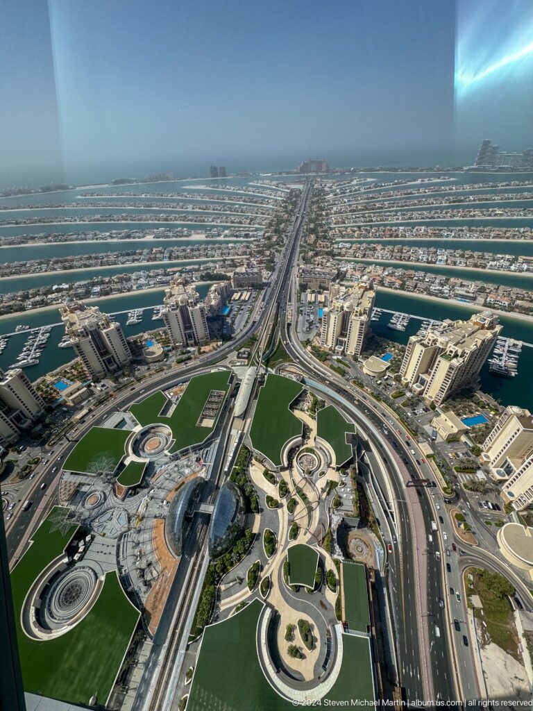 Symmetrical aerial view of Palm Jumeirah's gateway, marinas, towers, and central road.