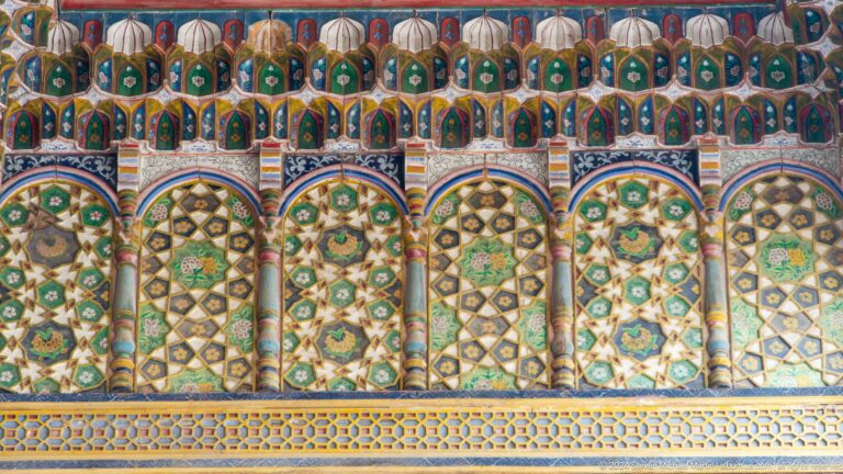 Repeating painted arches and geometric panels in green, blue, gold, and red.