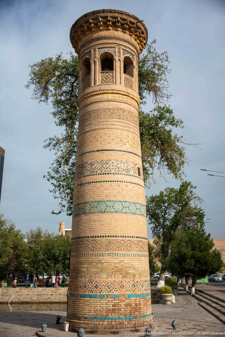 Brick minaret with patterned masonry and turquoise tile bands.