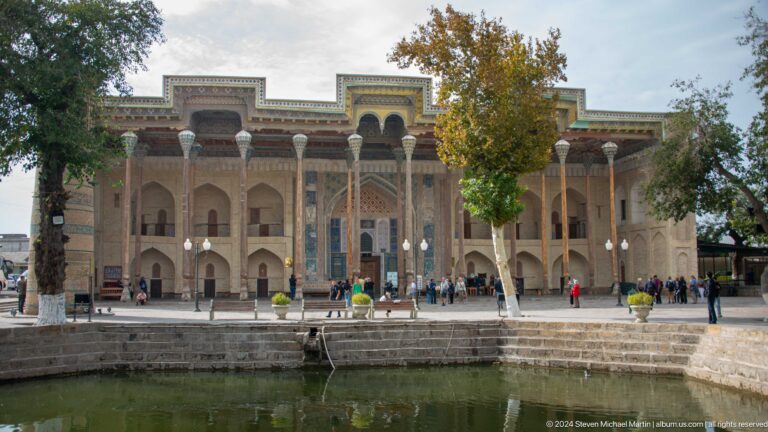 Bolo Hauz Mosque facing a rectangular pool with visitors in the forecourt.