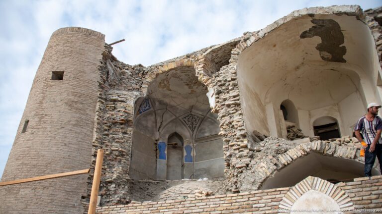 Damaged historic interior with exposed brickwork, plaster, and arched niches.