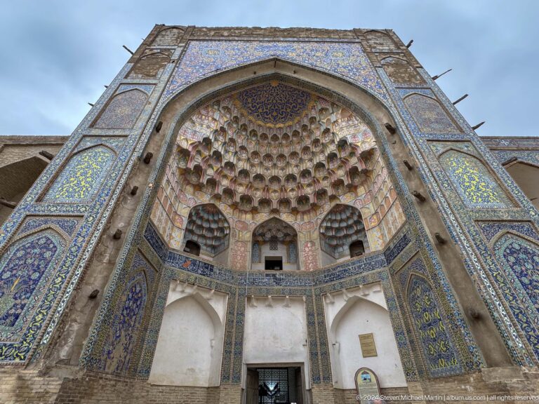 Upward view into a deep madrasa portal filled with muqarnas.
