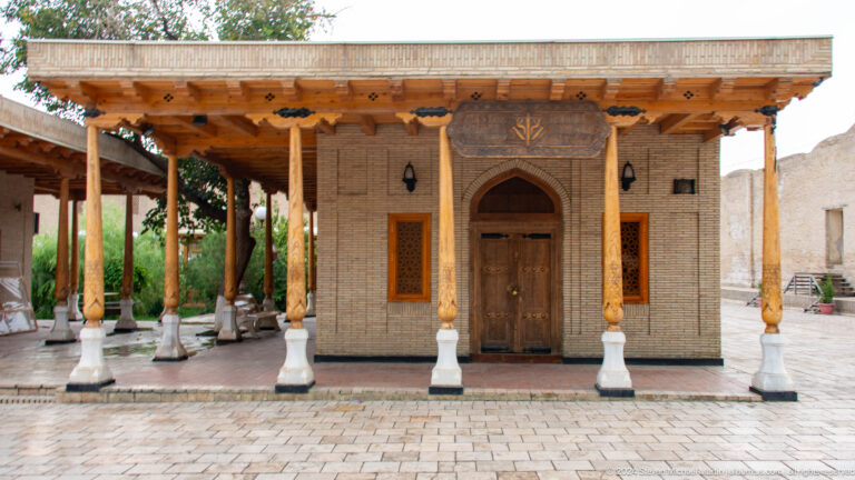 Wooden-columned veranda before carved doorway.
