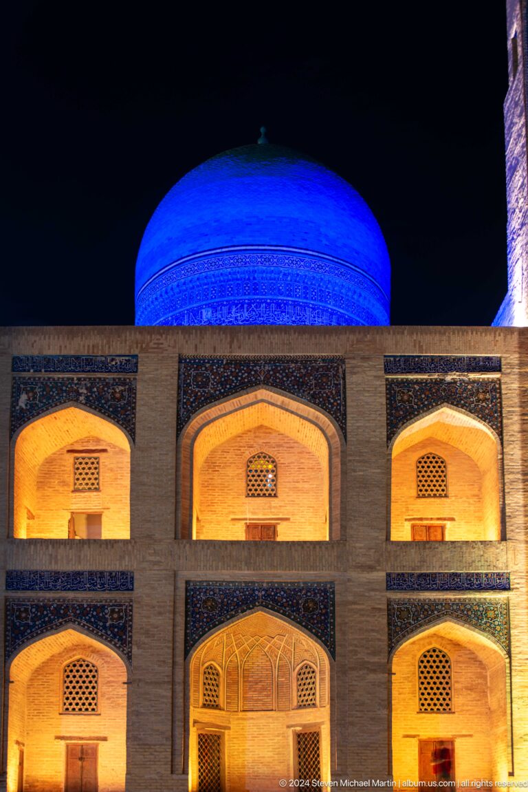 Three warm-lit pointed arches beneath a blue illuminated dome.